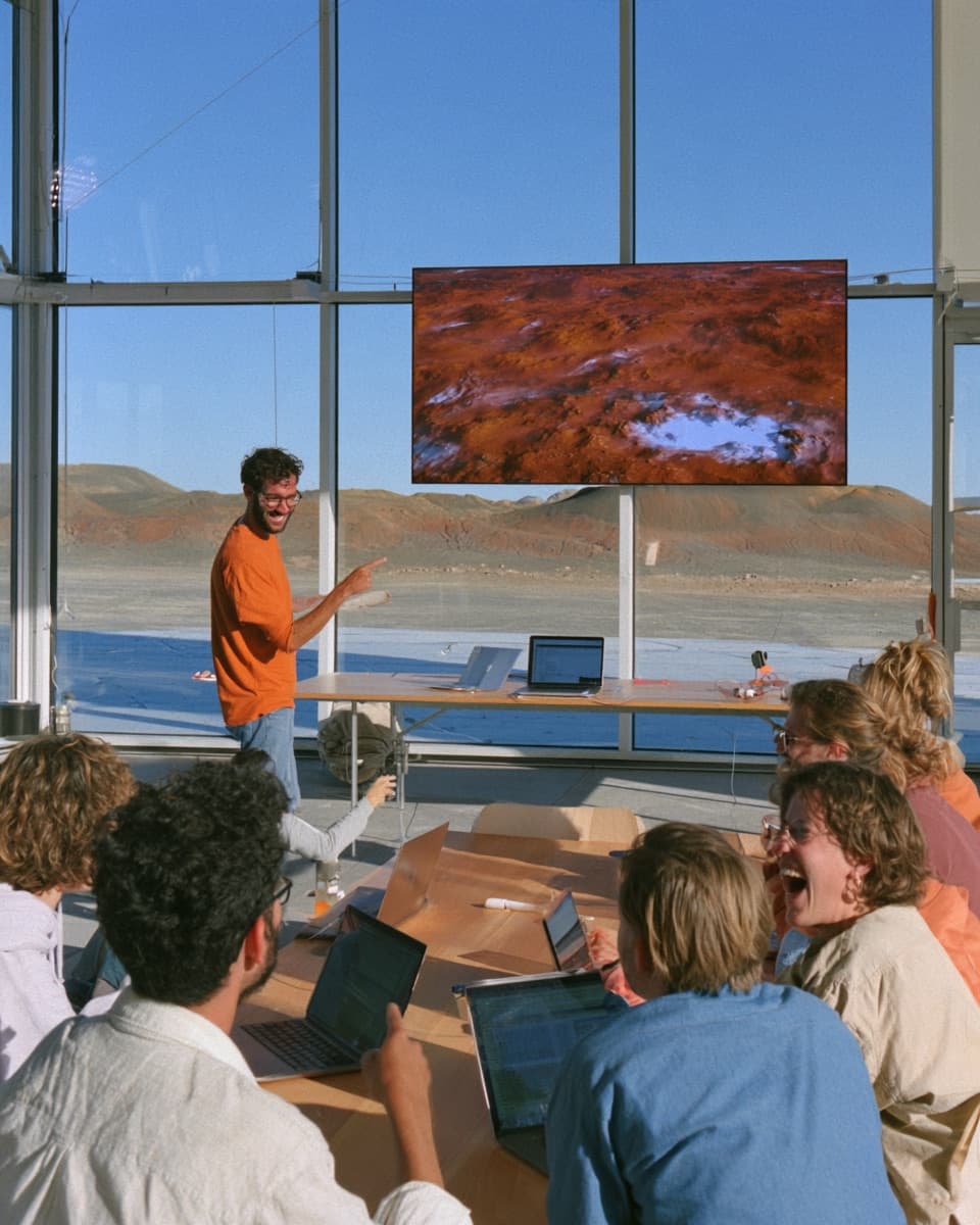 A young instructor leading a lively workshop around a table in a desert field station